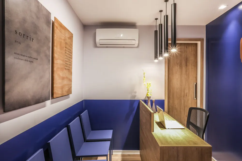 Recepção do escritório Cotrim Advogados com parede azul, cadeiras azuis e luminárias pendentes